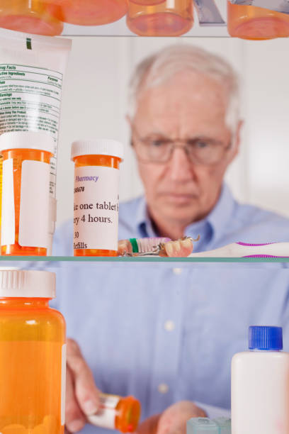 senior hombre adulto obtiene medicamentos de la caja. - medicine cabinet cabinet medicine bathroom fotografías e imágenes de stock
