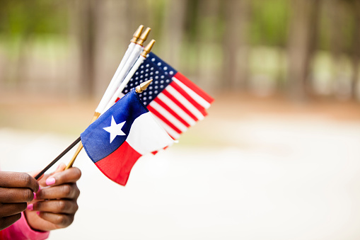 African descent woman holding the Texas, USA flags.  Various concepts including state and national pride.