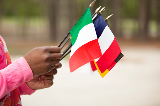 African descent woman holding flags that represent various countries throughout the world.  Various concepts of unity and global community, village.