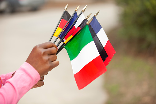African descent woman holding flags that represent various countries throughout the world.  Various concepts of unity and global community, village.