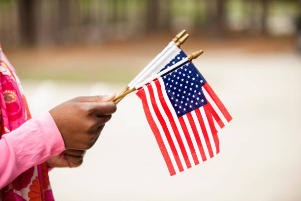 African descent woman holding USA flags.  Various concepts including national holidays and patriotism.