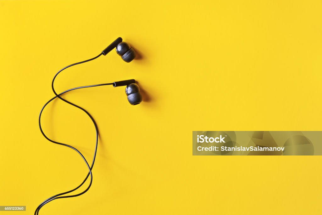 Headphones Flat lay concept: headphones on pastel backgrounds. Black headphones on a yellow background, top view, copyspace. Trendy colorful photo. Minimal style with colorful paper backdrop. Headphones Stock Photo