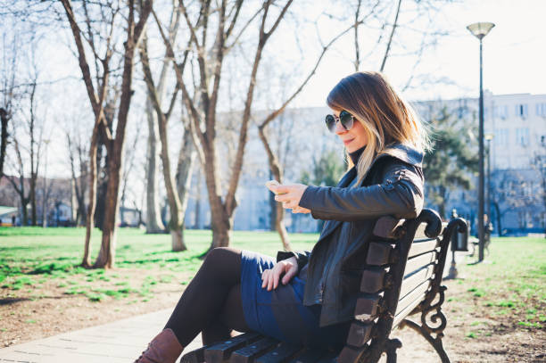 istock Young woman using smartphone in the park 655127640