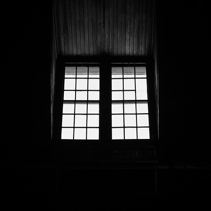 Light streams through windows at the Liberty State Park railroad and ferry terminal creating a beautiful silhouette. Image is black and white.