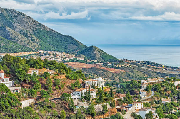 This great view of Mijas Spain overlooking the Mediterranean Sea with the variety of home on the hillside under a magnificant clouds sky is a great Postcard view.