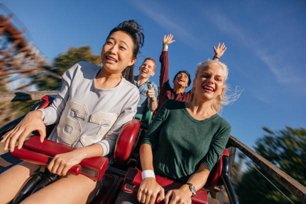 gruppe von freunden auf eine rasante achterbahn-fahrt - rollercoaster stock-fotos und bilder