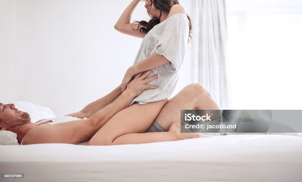 Sensual young couple on bed at home Sensual young couple on bed at home. Man lying on bed with woman on top. Women Stock Photo