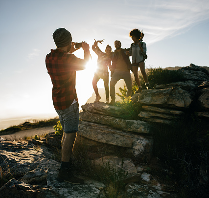 Group of friends on hike together in the countryside. Young man taking pictures of his friends.