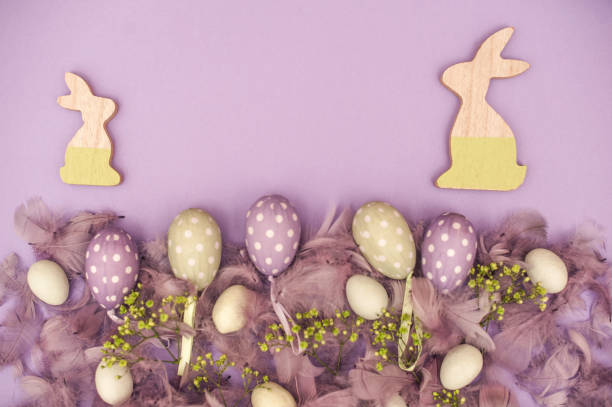 istock Two Wooden Bunnies and Easter Eggs on Purple Background 655140412