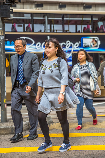Hong Kong, China - December 6, 2016: An asian family crosswalking the Causeway Bay road of the Yee Wo street, one the busiest downtown for fashion and luxury stores, located on the Henessy road.