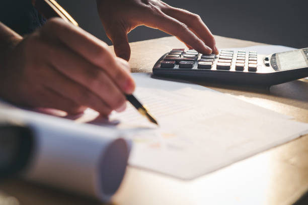 istock calculator and Financial data analyzing hand writing and counting in office on wood desk 655224306