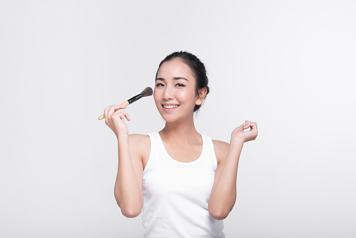 Portrait of attractive young Asian woman with beautiful skin holding brush for make up.