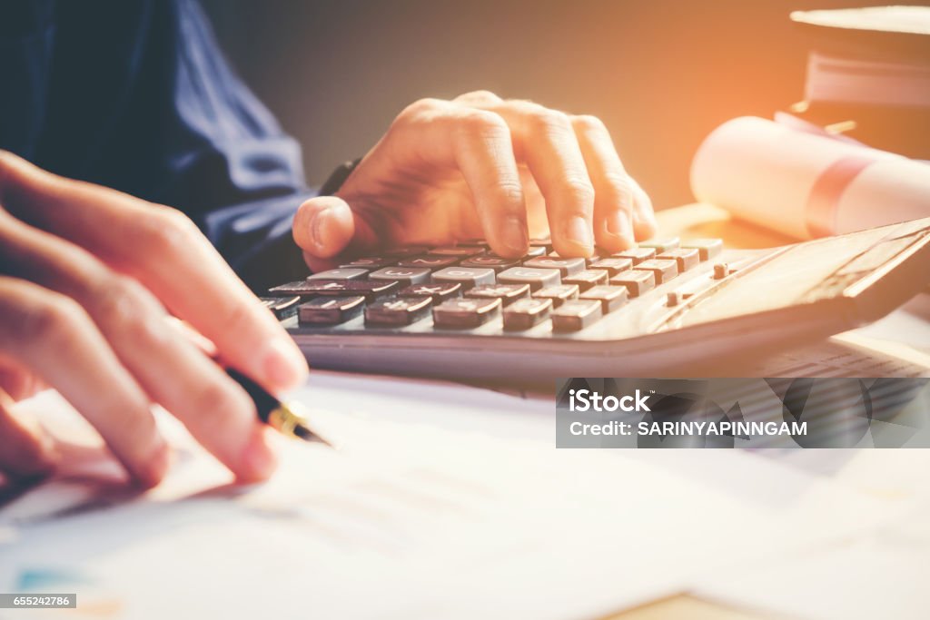 Businessman's hands with calculator at the office and Financial data analyzing  counting on wood desk Paycheck Stock Photo