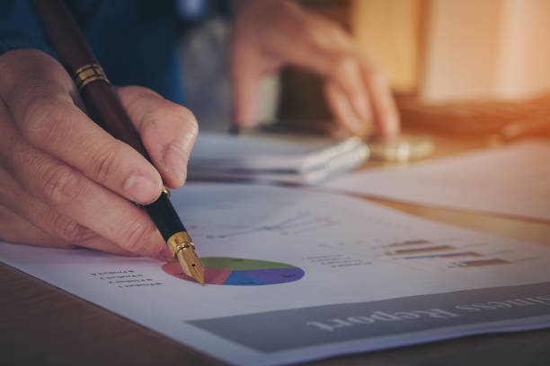 istock hand with a pen writing on the business paper. Report chart 655243496
