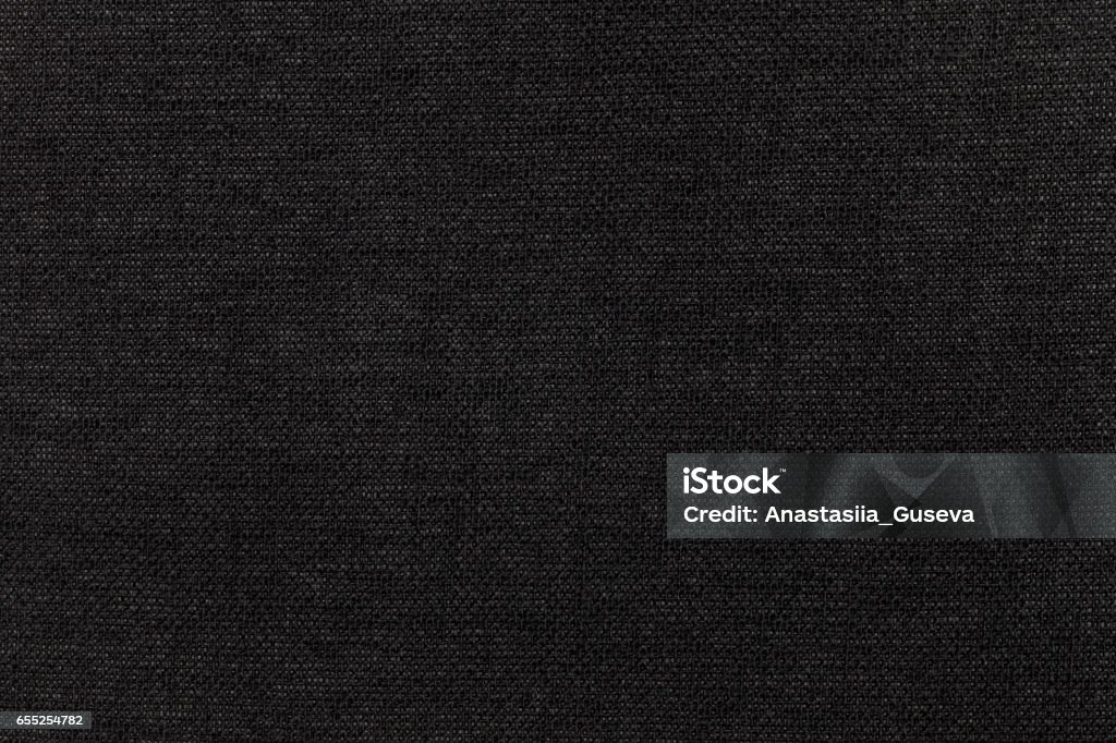 Black background from textile material. Fabric with natural texture. Backdrop. Black background from a textile material. Fabric with natural texture. Cloth backdrop. Black Color Stock Photo
