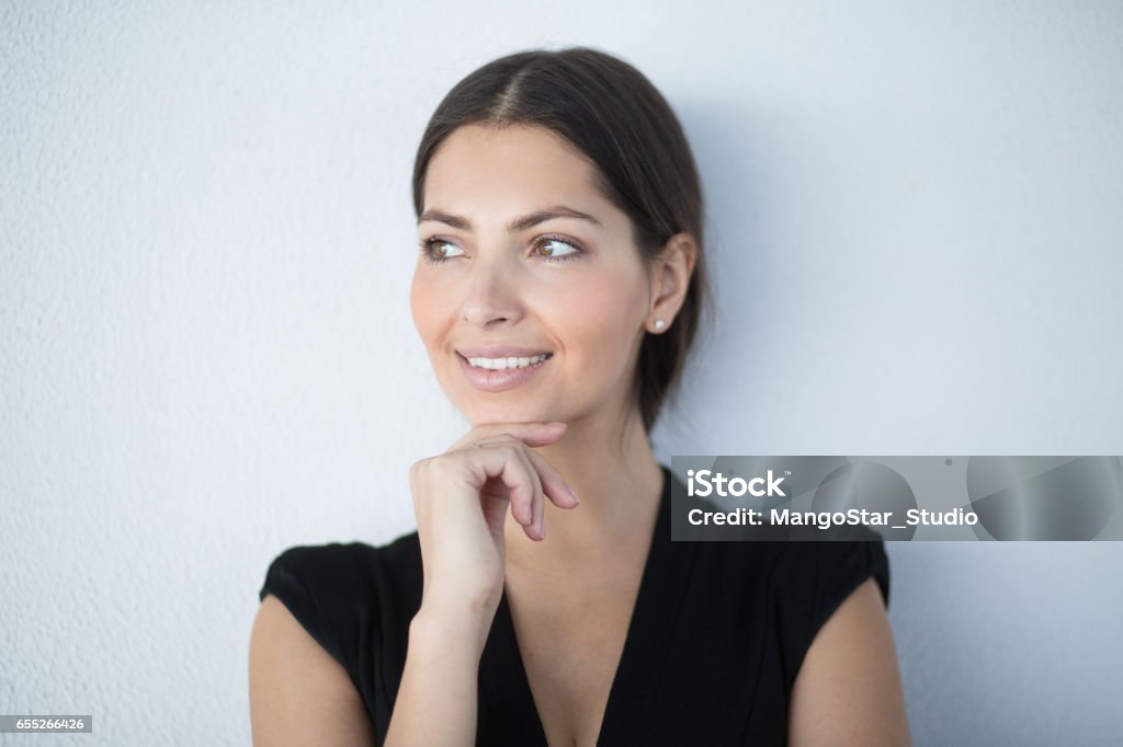 Closeup of Smiling Pensive Gorgeous Business Woman Closeup portrait of pensive beautiful middle-aged business woman wearing dress, touching chin and looking away. Isolated front view on grey background. Mature Women Stock Photo