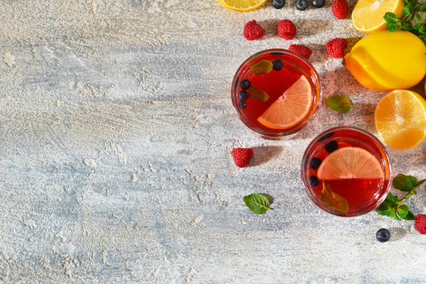 Cold berry drink with lemon and mint on a concrete background