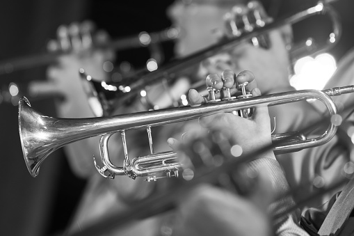 Trumpet in the hands of a musician in the band closeup in black and white