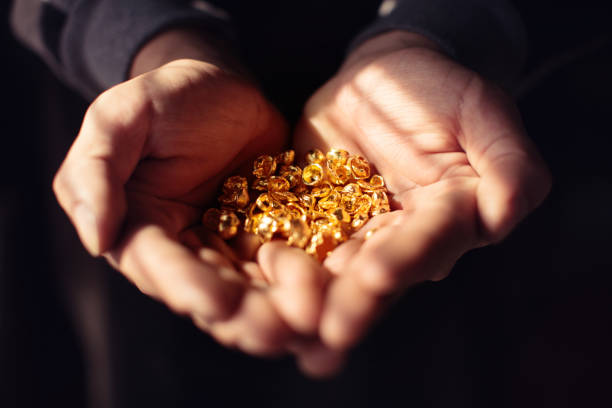 Hands full of pure raw gold over dark background