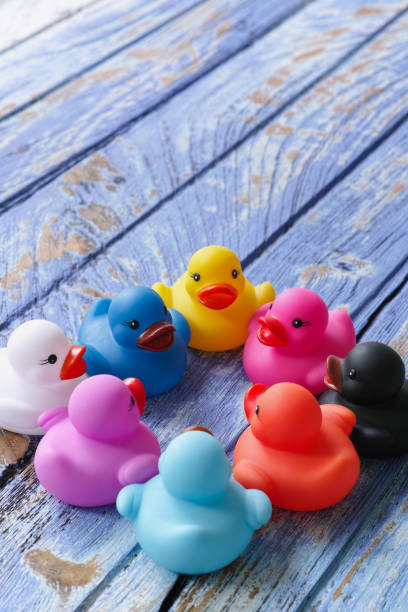 istock Group of multi-colored rubber ducks sit together in a circle on an old wooden blue table. 655287724