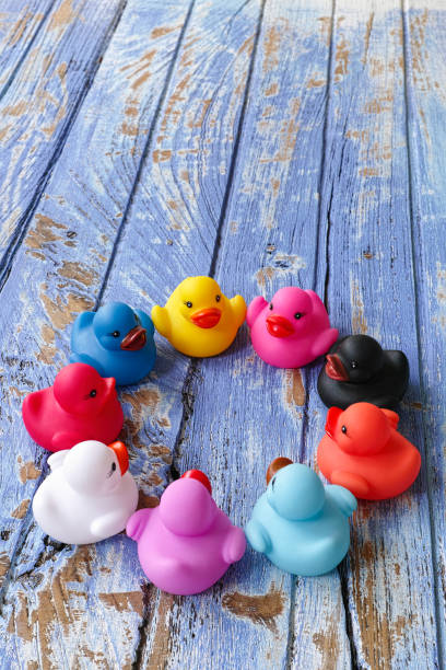 istock Group of multi-colored rubber ducks sit together in a circle on an old wooden blue table. 655287782