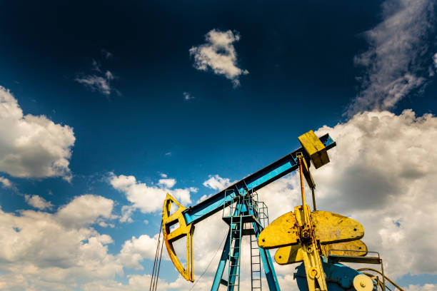 campo de petróleo com tomada de bomba, perfilado no céu azul com nuvens brancas, em um dia ensolarado - oil pump oil industry alberta equipment - fotografias e filmes do acervo