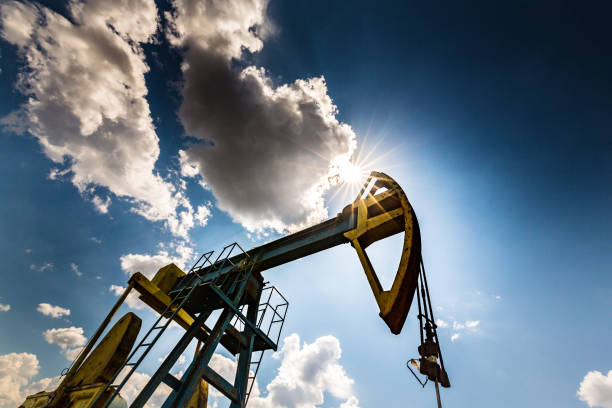 campo de petróleo com tomada de bomba, perfilado no céu azul com nuvens brancas, em um dia ensolarado - oil pump oil industry alberta equipment - fotografias e filmes do acervo