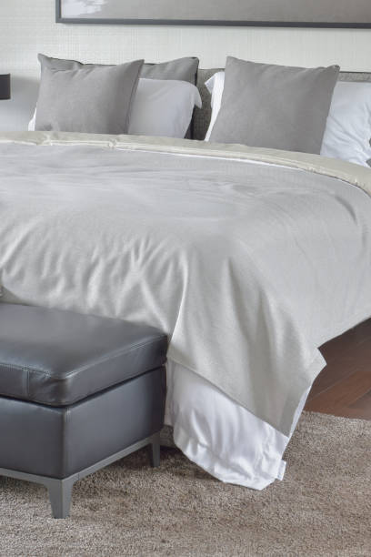istock Beige blanket on comfy bed with black leather ottoman 655290878