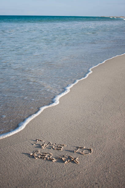 istock Time to relax written on sand on clear beach 655313496