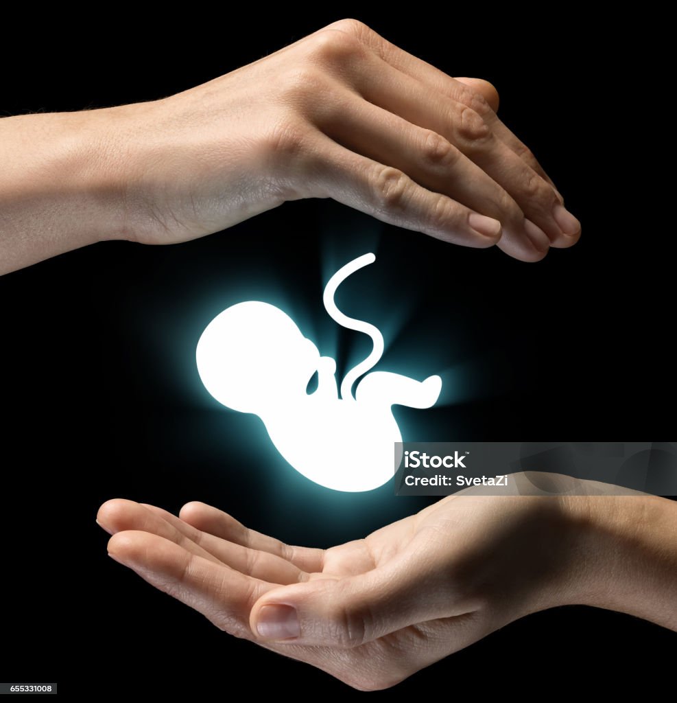 Concept of caring for baby. Isolated image of two hands on black background. Baby icon in the center, as a symbol of caring for baby and mother. Concept of caring for baby. Assistance Stock Photo