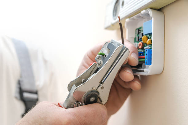 Installing a programmable room thermostat. Installing a programmable room thermostat. Man's hands strips insulation of the wire for connecting the device later. thermostat stock pictures, royalty-free photos & images