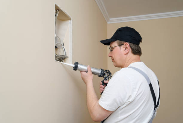 istock Man puts glue with caulk gun. 655332066