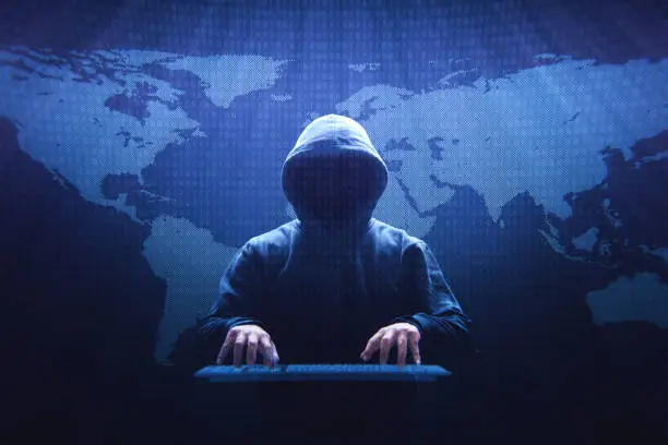 Anonymous computer hacker sitting in front of a virtual screen.