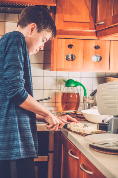 istock Boy Cutting Cheese for Cream Sauce, Southern Europe 655346356