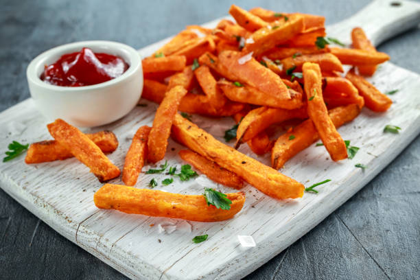Healthy Homemade Baked Orange Sweet Potato Fries with ketchup, salt, pepper on white wooden board Healthy Homemade Baked Orange Sweet Potato Fries with ketchup, salt, pepper on white wooden board. sweet potato photos stock pictures, royalty-free photos & images