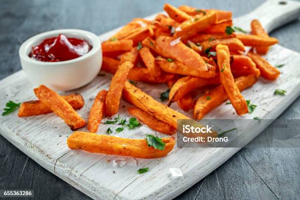 Healthy Homemade Baked Orange Sweet Potato Fries With Ketchup Salt Pepper On White Wooden Board Stock Photo - Download Image Now