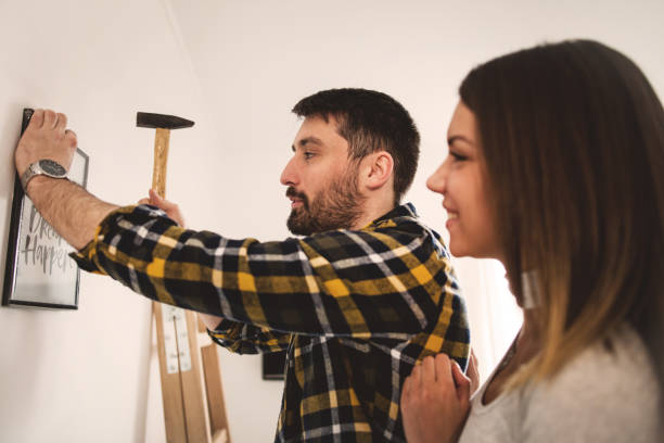 istock Couple hanging picture on wall 655370800