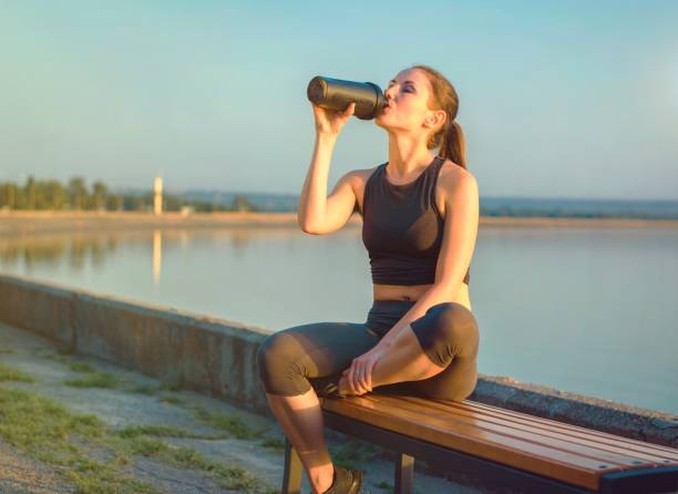 istock Women drinking from a shaker at sunset at the river on the background. 655377698