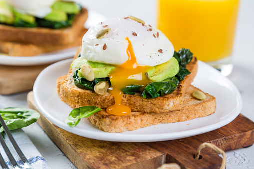 Sandwich with spinach, avocado and egg on wood background
