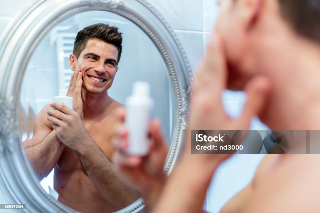 Healthy positive male treating sking with lotion after shaving Men Stock Photo