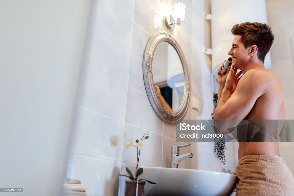 Happy handsome man shaving in bathroom Adult Stock Photo