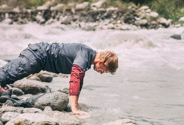istock Traveler man washes his face with cold water in mountain river 655403716