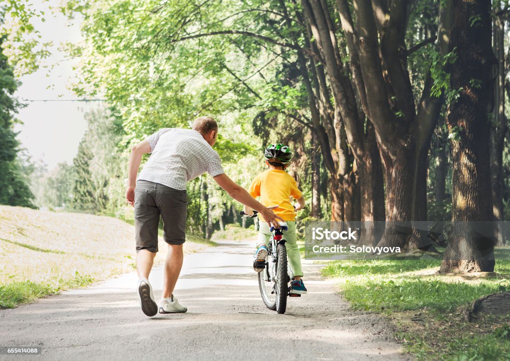 Père aider fils fils faites du vélo - Photo de Faire du vélo libre de droits