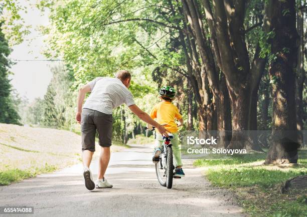 Photo libre de droit de Père Aider Fils Fils Faites Du Vélo banque d'images et plus d'images libres de droit de Faire du vélo - Faire du vélo, Vélo, Apprentissage