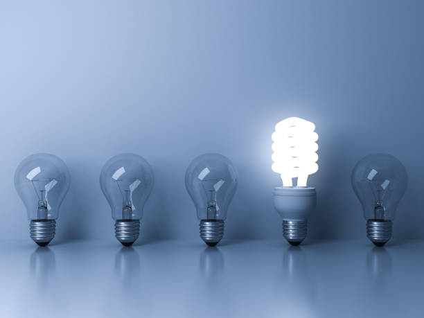 istock Eco energy saving light bulb , one glowing fluorescent lightbulb standing out from unlit incandescent bulbs reflection on blue background , individuality and different ideas concepts 3D rendering 655446978