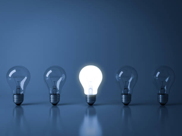istock One glowing light bulb standing out from the crowd unlit incandescent bulbs on dark blue background with reflection and shadow , individuality and different creative idea concepts 3D rendering 655446996