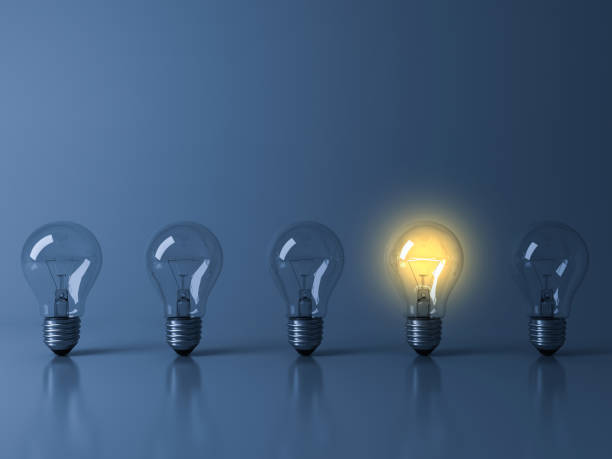 istock One yellow glowing light bulb standing out from the unlit incandescent bulbs on dark blue background with reflection and shadow , individuality and different creative idea concepts 3D rendering 655449088