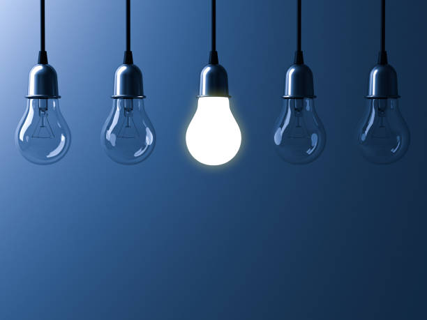 istock One hanging light bulb glowing different and standing out from unlit incandescent bulbs with reflection on dark blue background , leadership and different business creative idea concept 3D rendering 655449182