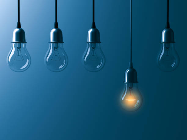 istock One hanging light bulb glowing different and standing out from unlit incandescent bulbs with reflection on dark cyan background , leadership and different business creative idea concept 3D rendering 655449196