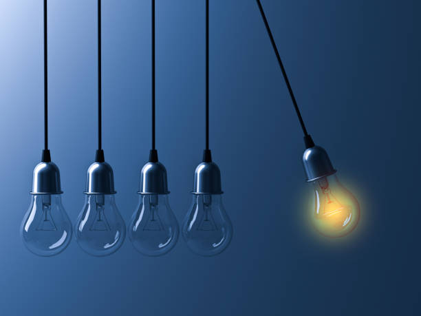 istock One hanging light bulb glowing different and stand out from unlit incandescent bulbs like newtons cradle on dark blue background, leadership and different business creative idea concept 3D rendering 655449214